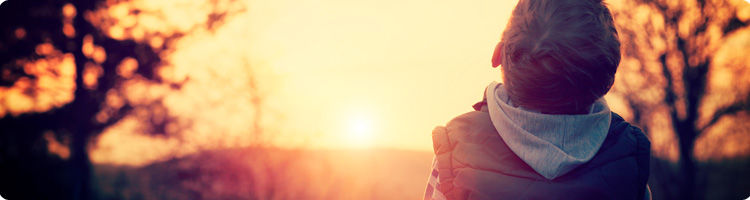 Boy looking up to the sunset sky